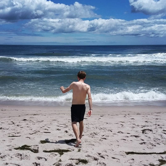 A young man walking on the beach towards the Atlantic Ocean